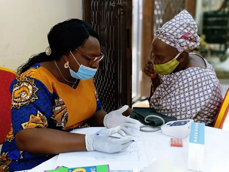 A nurse checking an elderly woman at a monthly health check